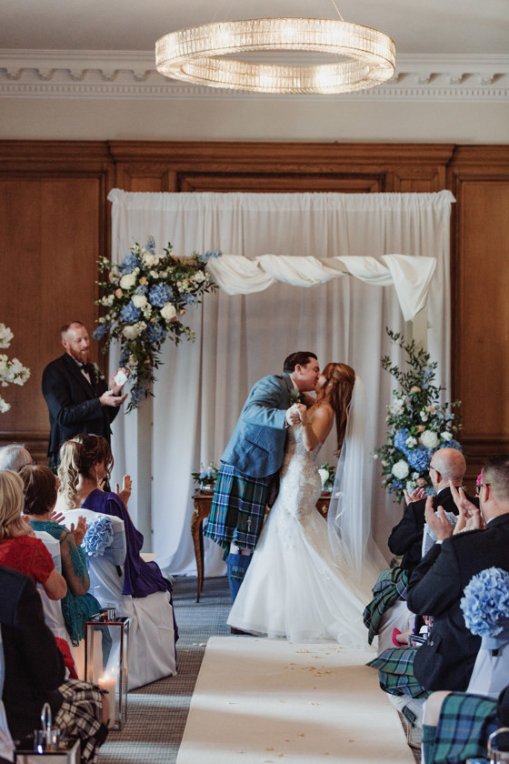 Bride and groom kiss at the altar at Dean Banks at The Pompadour while guests clap